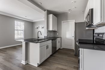 An empty kitchen with white cabinets and black counter tops